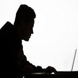 一个人坐在桌上的笔记本电脑上工作的黑白轮廓.
